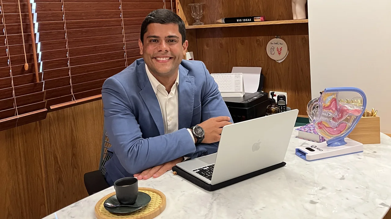 Dr. Vinícius Araújo em seu consultório com um modelo anatômico da pelve.
